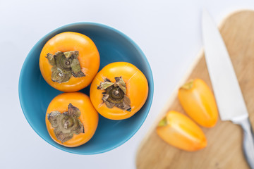 selective focus of persimmons on blue glass plate and slices on cutting board