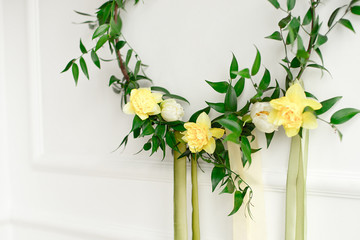 Close-up green wreath of narcissus and plants on the white wall
