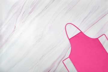 Pink apron on marble background with natural pattern. Flat lay. Top view