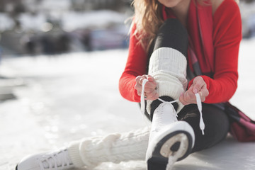 Woman tie shoelaces figure skates at ice rink close-up