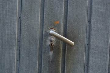 A metal door handle on a metal fence gate