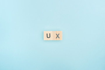 top view of ux lettering made of wooden cubes on blue background