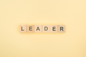 top view of leader lettering made of wooden cubes on yellow background