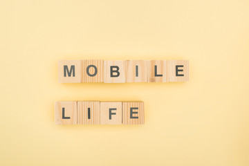 top view of mobil life lettering made of wooden cubes on yellow background