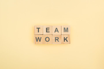 Fototapeta na wymiar top view of team work lettering made of wooden blocks on yellow background