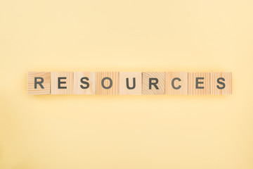 top view of resources lettering made of wooden cubes on yellow background