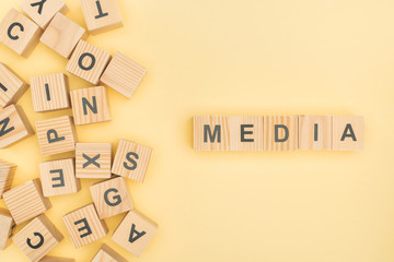 top view of media lettering with wooden cubes on yellow background