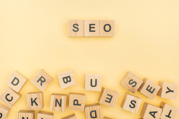 top view of seo lettering with wooden cubes on yellow background