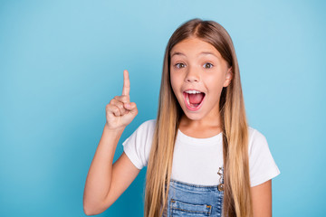 Close-up portrait of her she nice cute lovely smart clever intelligent attractive funny straight-haired blonde pre-teen girl pointing up opened mouth isolated on blue pastel background