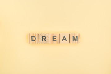 top view of dream lettering made of wooden cubes on yellow background