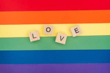 top view of love lettering made of  wooden cubes on paper rainbow background