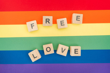 top view of free love lettering made of  wooden cubes on paper rainbow background