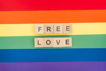 top view of free love lettering made of wooden blocks on paper rainbow background