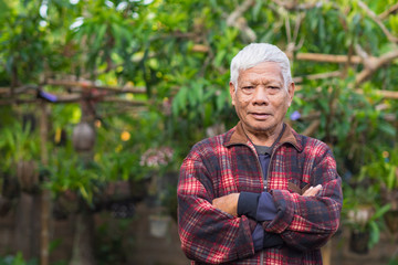 Portrait of elderly man standing in home garden.