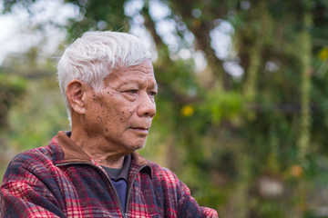 Portrait of elderly man standing in home garden.