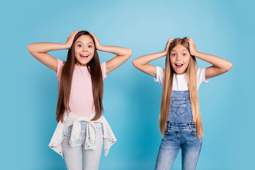 Fototapeta na wymiar Portrait of two people nice cute amazed attractive charming cheerful funny straight-haired pre-teen girls touching head great news wow cool isolated over blue pastel background