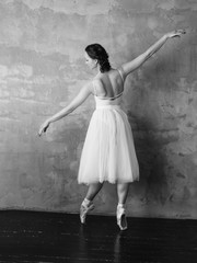 Ballet dancer ballerina in beautiful white dress tutu skirt posing in loft studio