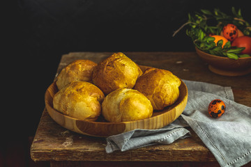 Homemade buns in wooden plate standing with colored yellow orange eggs