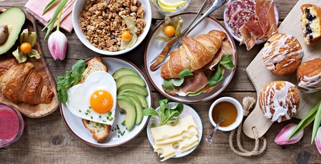 Breakfast food table. Festive brunch set, meal variety with fried egg, croissant sandwich, granola and smoothie. Overhead view