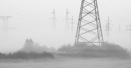 Transmission towers in the fog. High Voltage power line silhouette