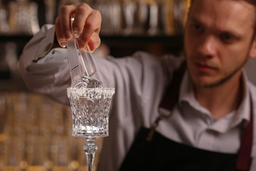 Margarita alcohol cocktail with lime ice. Alcohol cocktail on black background surface.  Barmen is making Margarita