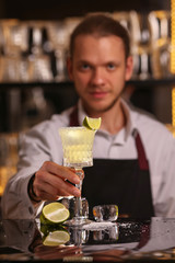 Margarita alcohol cocktail with lime ice. Alcohol cocktail on black background surface.  Barmen is making Margarita