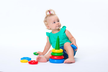 Obraz premium Cute kid blonde girl playing with color pyramid toy isolated on white background. Happy childhood and pre-school development of children