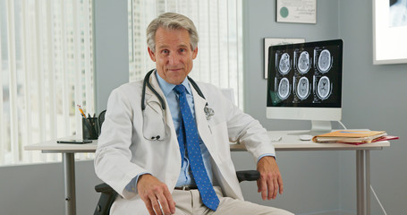 Caucasian male doctor sitting at desk and talking to camera with brain scans on his computer. Pov shot of physician having conversation directly to viewer Video Chat
