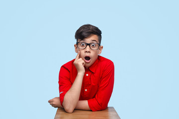 Shocked schoolboy sitting at desk