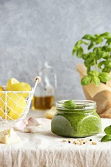 Pesto.Traditional italian basil pesto sauce in glass jar over rustic wooden table. 