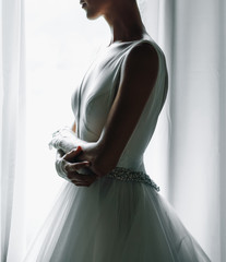 Bride's morning portrait. Bride dressed like a balerina stands before a bright window © IVASHstudio