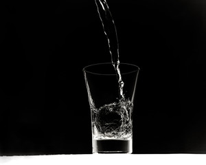 Glass pouring clean water on a black background