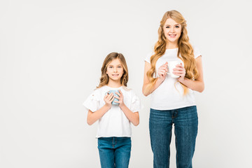 smiling mother and cute child holding coffee cups on white background