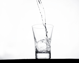 glass pouring clean water on a light background