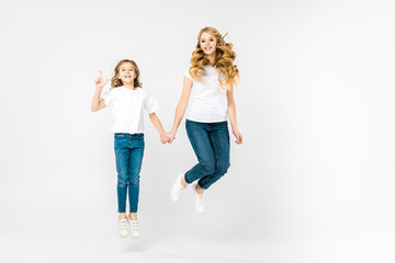 Obraz premium happy mother with adorable daughter jumping on white background