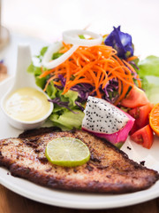 Grilled fish steak with salad with white plate on marble table.
