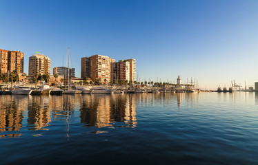 Fototapeta na wymiar Sunny skyline reflection on the water of the port of malaga