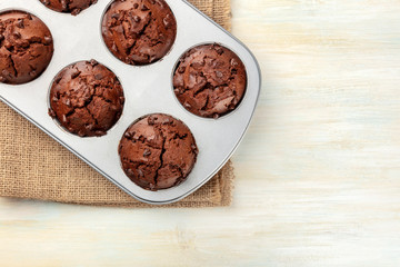 Chocolate muffins in a baking mould, shot from above on a light background with a place for text