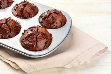 Chocolate muffins in a baking mold on a light background with copy space