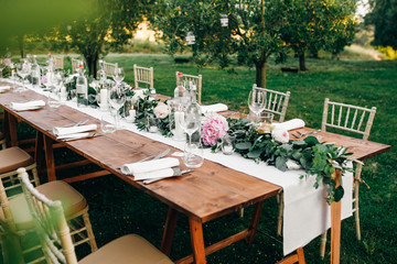Floral garland of eucalyptus and pink flowers lies on the table for wedding reception. Italian...
