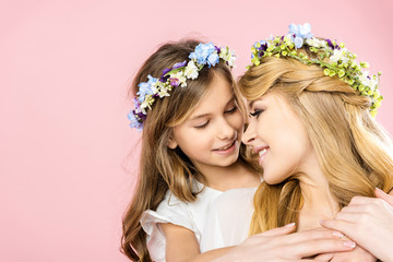 adorable smiling child embracing beautiful happy mother on pink background