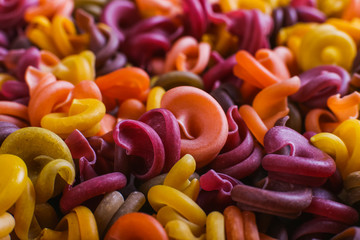Multi-colored macaroni of an unusual form with natural vegetable dyes. Background closeup.