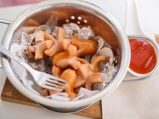 Fried sausages in aluminium bowl serves with tomato sauce on table, menu for kids.