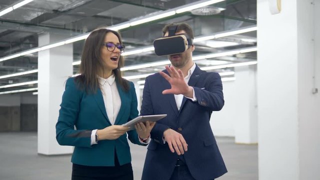 Empty hall is being shown to a man in VR-glasses by his estate agent