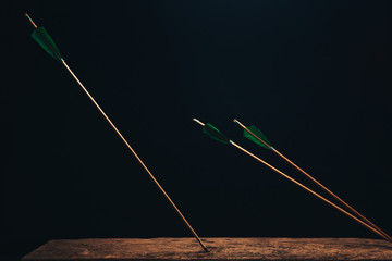 Old wood arrow on a wooden table. Beautiful dark background. Medieval weapons are handmade.