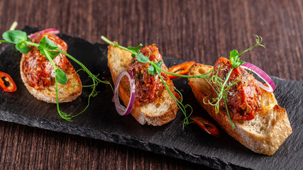 The concept of Mexican cuisine. Beef tartare with parsley, French mustard beans on baguette...
