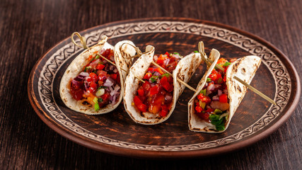 Concept of Mexican cuisine. Mexican appetizer Tacos with vegetables, beans, paprika, chilli peppers on fried unleavened bread cakes. Taco for veterinarians. Background image.