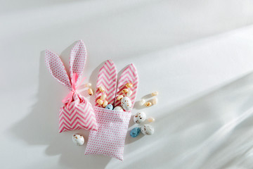 Easter Bunny bags with treats, candy, chocolate eggs on white background. Happy Easter concept.