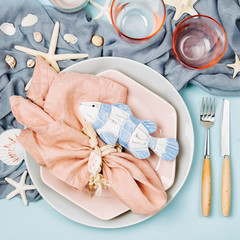 Tableware and sea decorations for serving a festive table. Plates, wine glasses and cutlery on blue...
