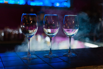Two empty wine glasses arranged on the counter before the party to start in restaurant or bar with smoke 